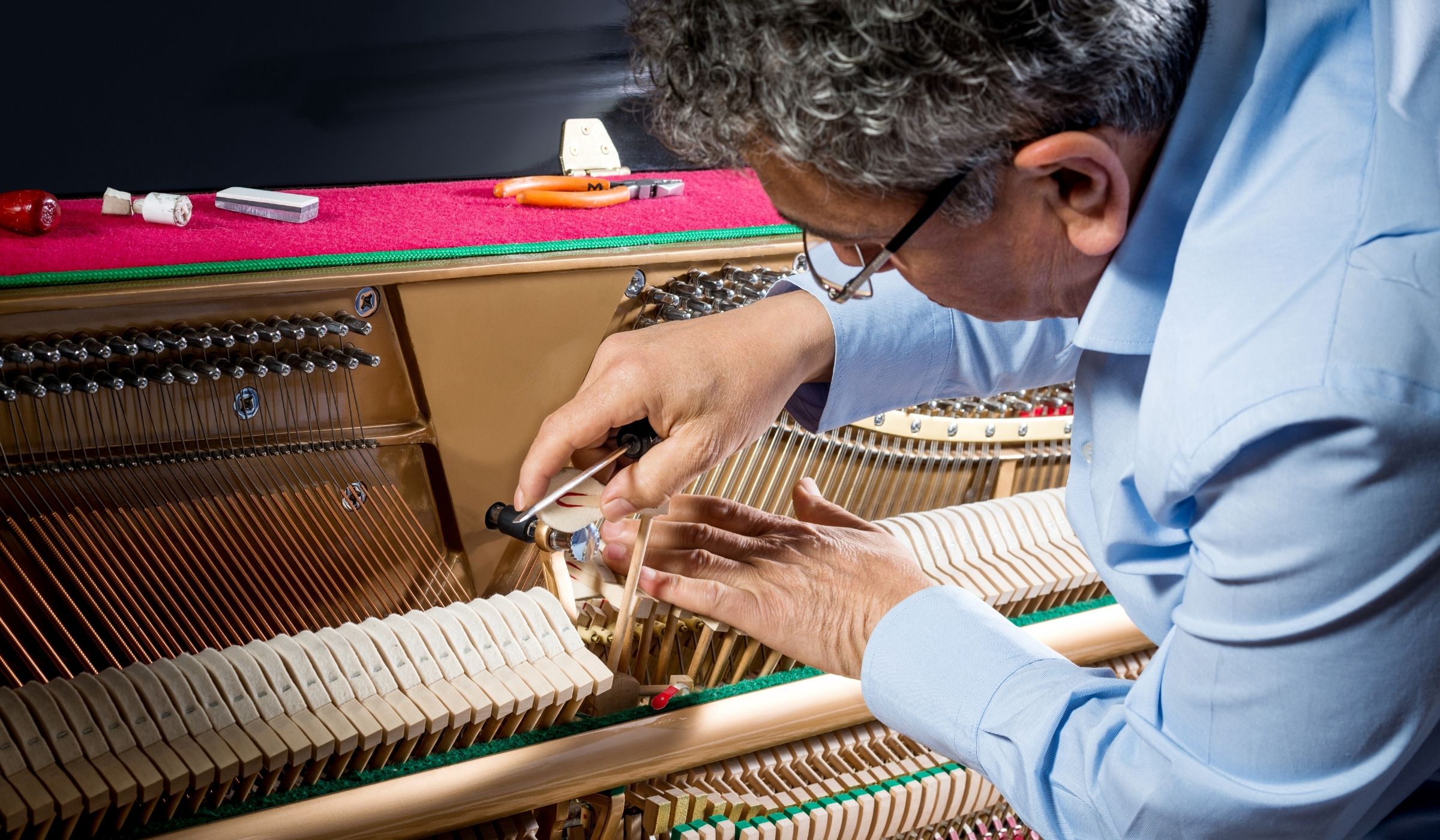 Técnico dando mantenimiento a un piano